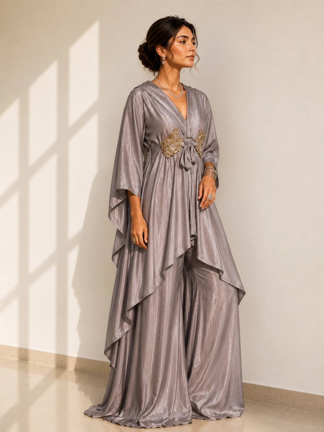 Woman in an elegant onion-colored layered kurti with golden waist detail and matching palazzo pants.