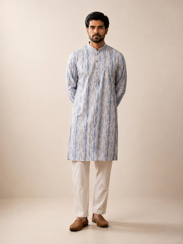 Man in a dust blue printed kurta, white pajama, and brown loafers.