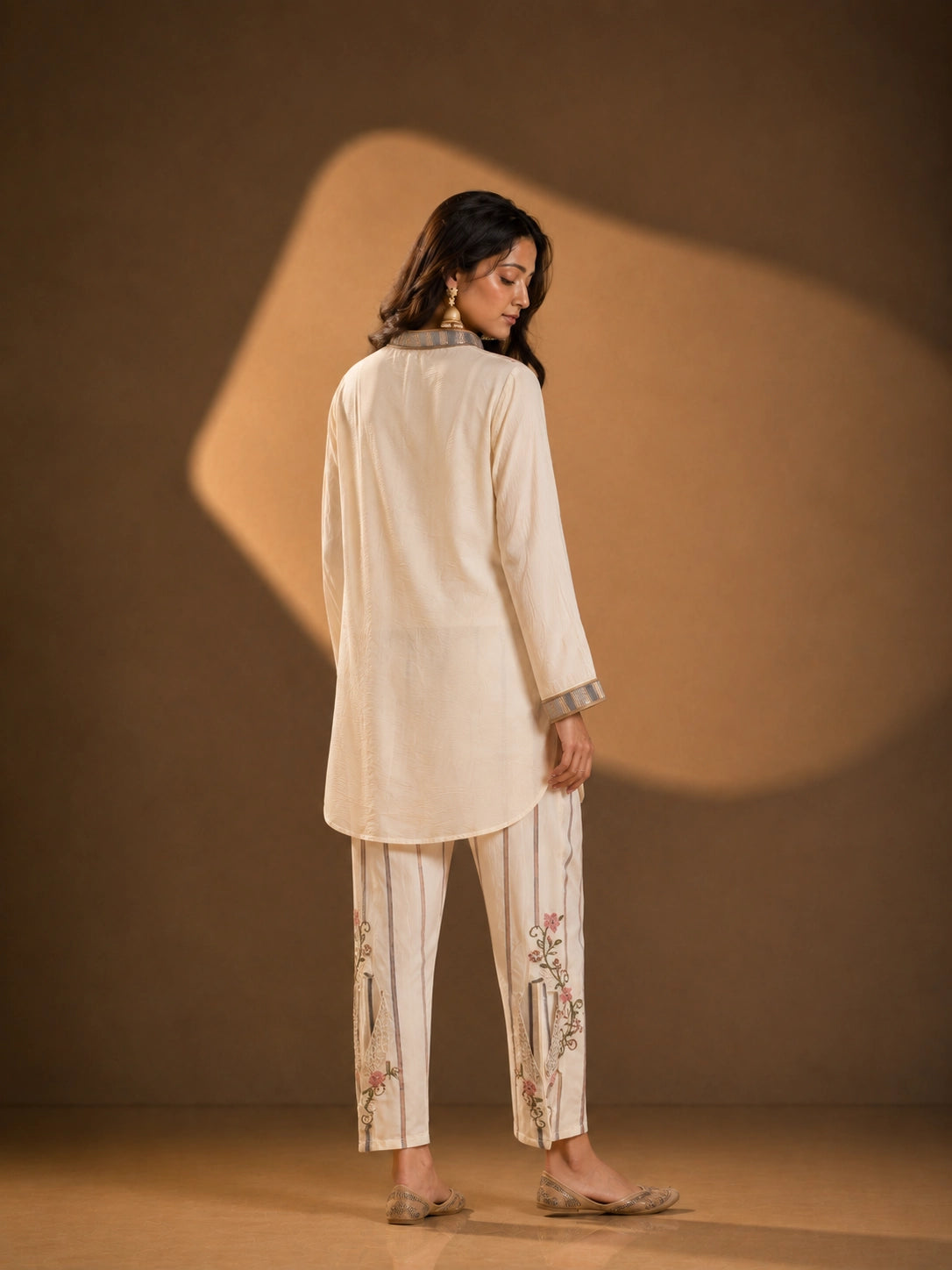 Woman wearing an elegant cream embroidered button-down kurti with striped collar and cuffs.