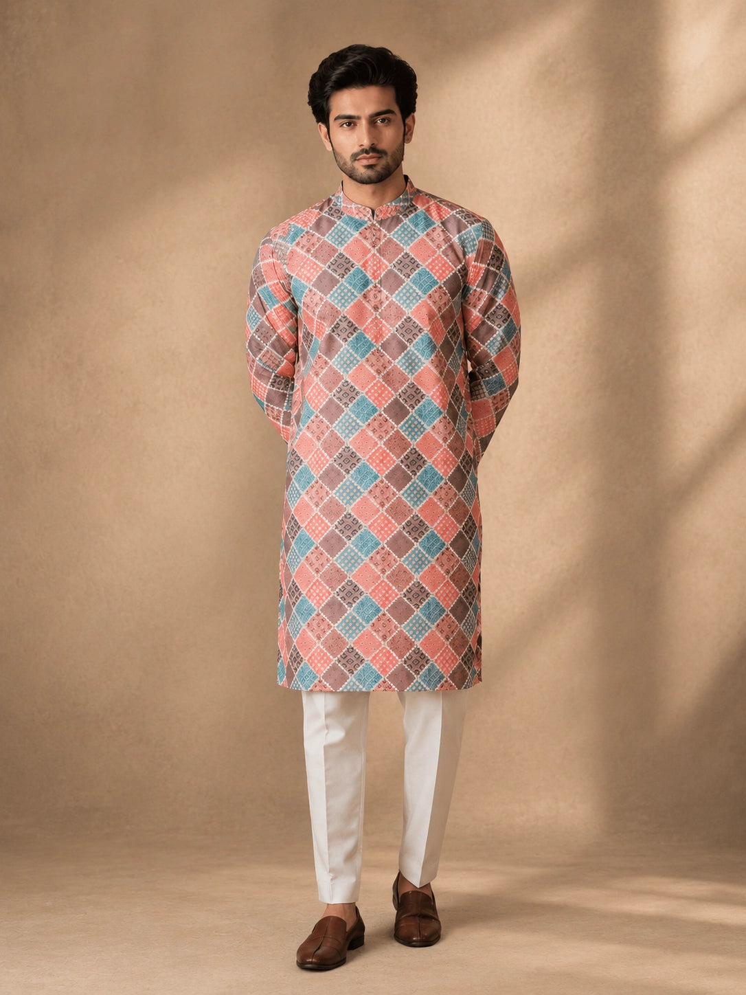 Man in a vibrant geometric diamond print kurta, white pajama, and brown loafers.