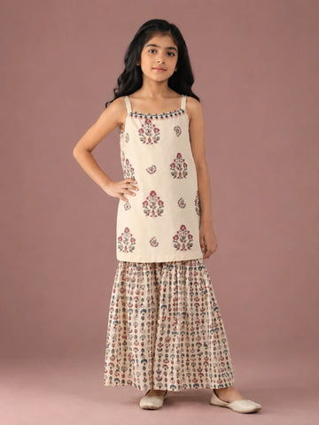 Young girl in a cream floral print strappy top and matching flared sharara set.