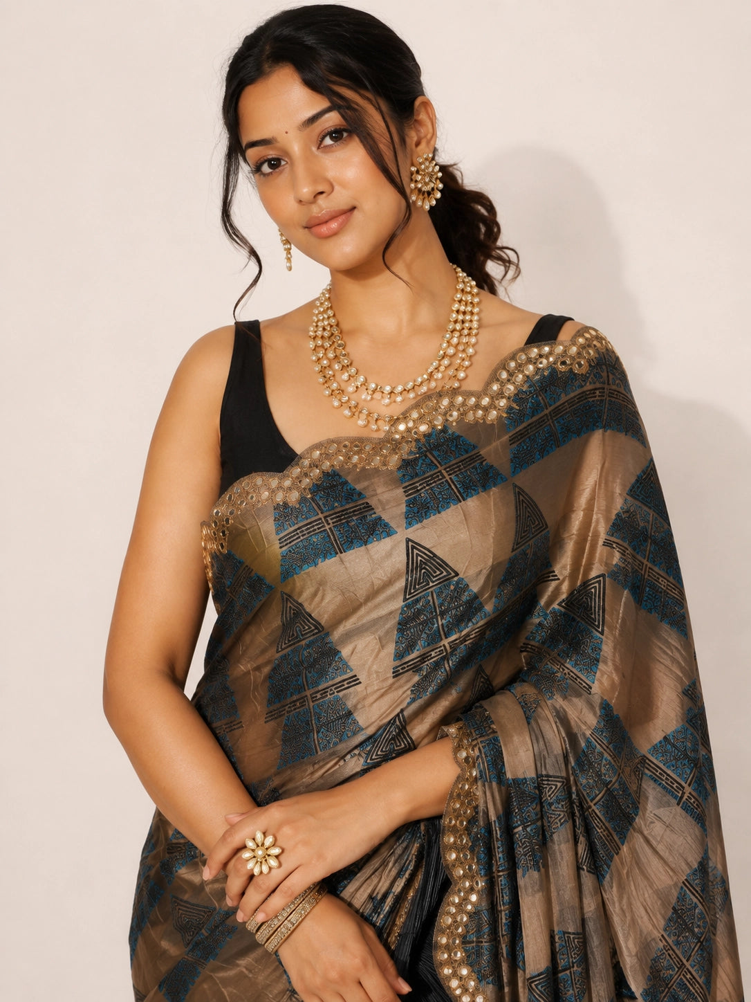Woman in elegant grey and bronze  saree with geometric patterns and embellished border.