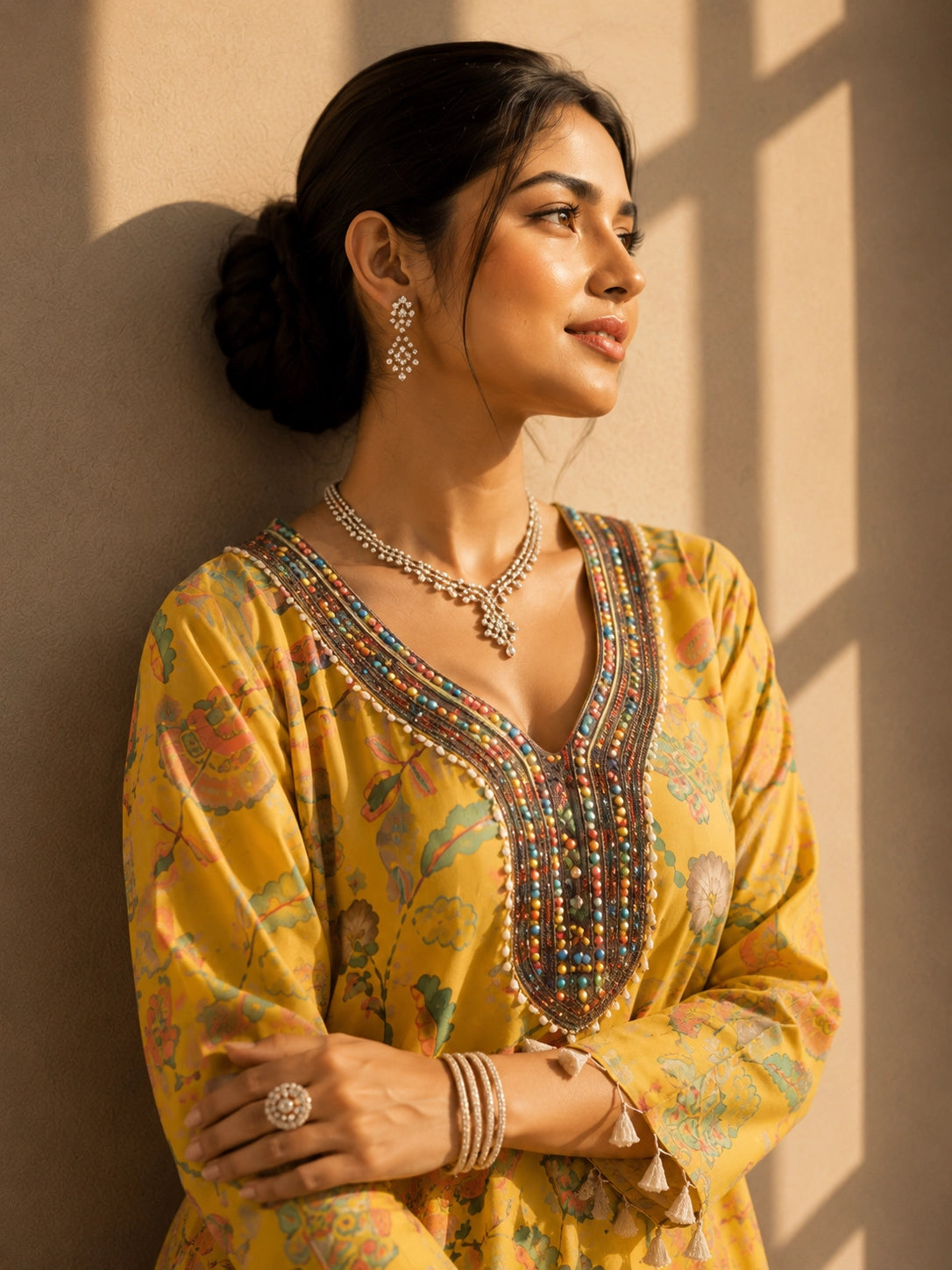 Woman wearing a vibrant yellow floral kurti with intricate embroidered V-neck and tassels.