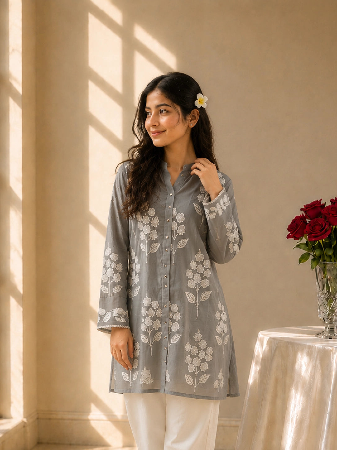 Woman wearing a sky blue embroidered tunic with white pants and sandals.