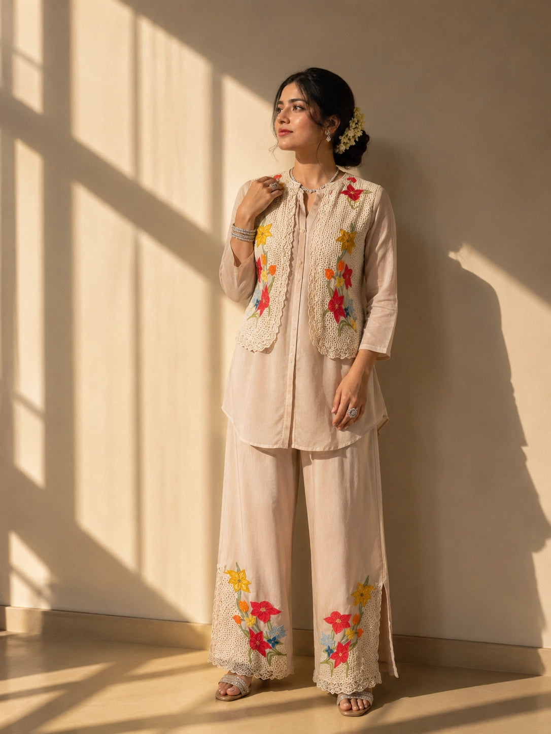 Woman in a beige kurta set with a short floral embroidered jacket and palazzo pants.