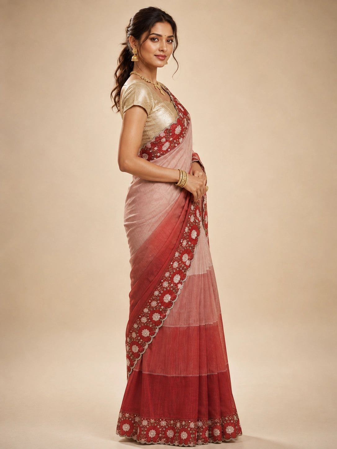 Woman in an elegant red ombre  saree with intricate white floral embroidery.