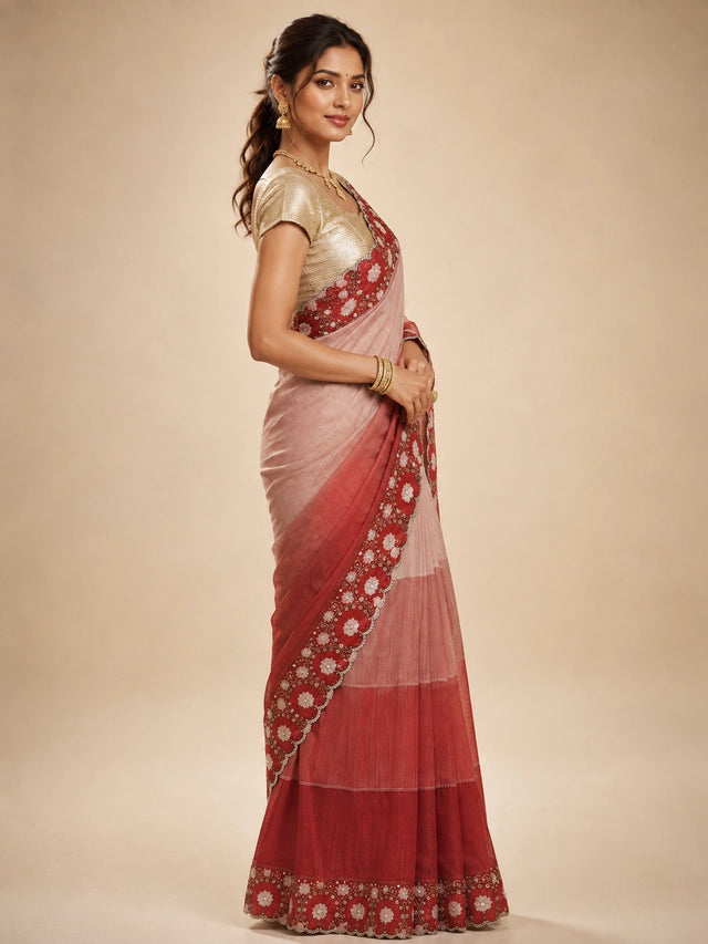 Woman in an elegant red ombre  saree with intricate white floral embroidery.