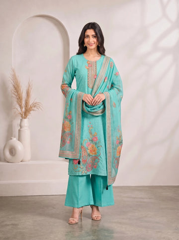 Woman wearing a teal kurti set with floral prints and matching palazzo pants, draped with a dupatta.