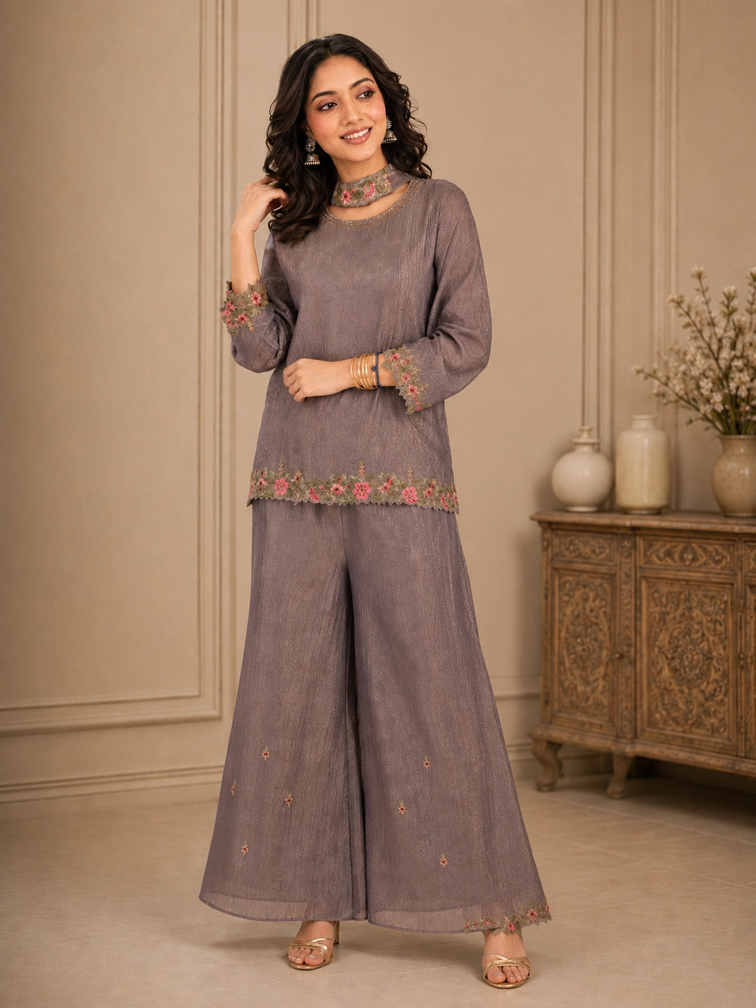 Woman wearing a pink embroidered choker neck Sharara with floral details on sleeves and hem.