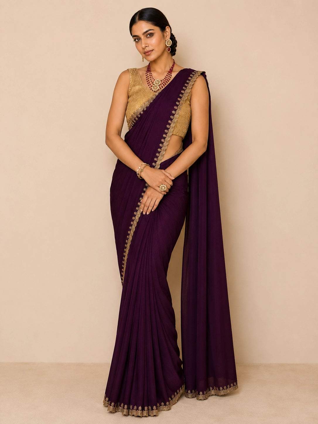 Woman in elegant wine saree with golden embroidered border and matching blouse