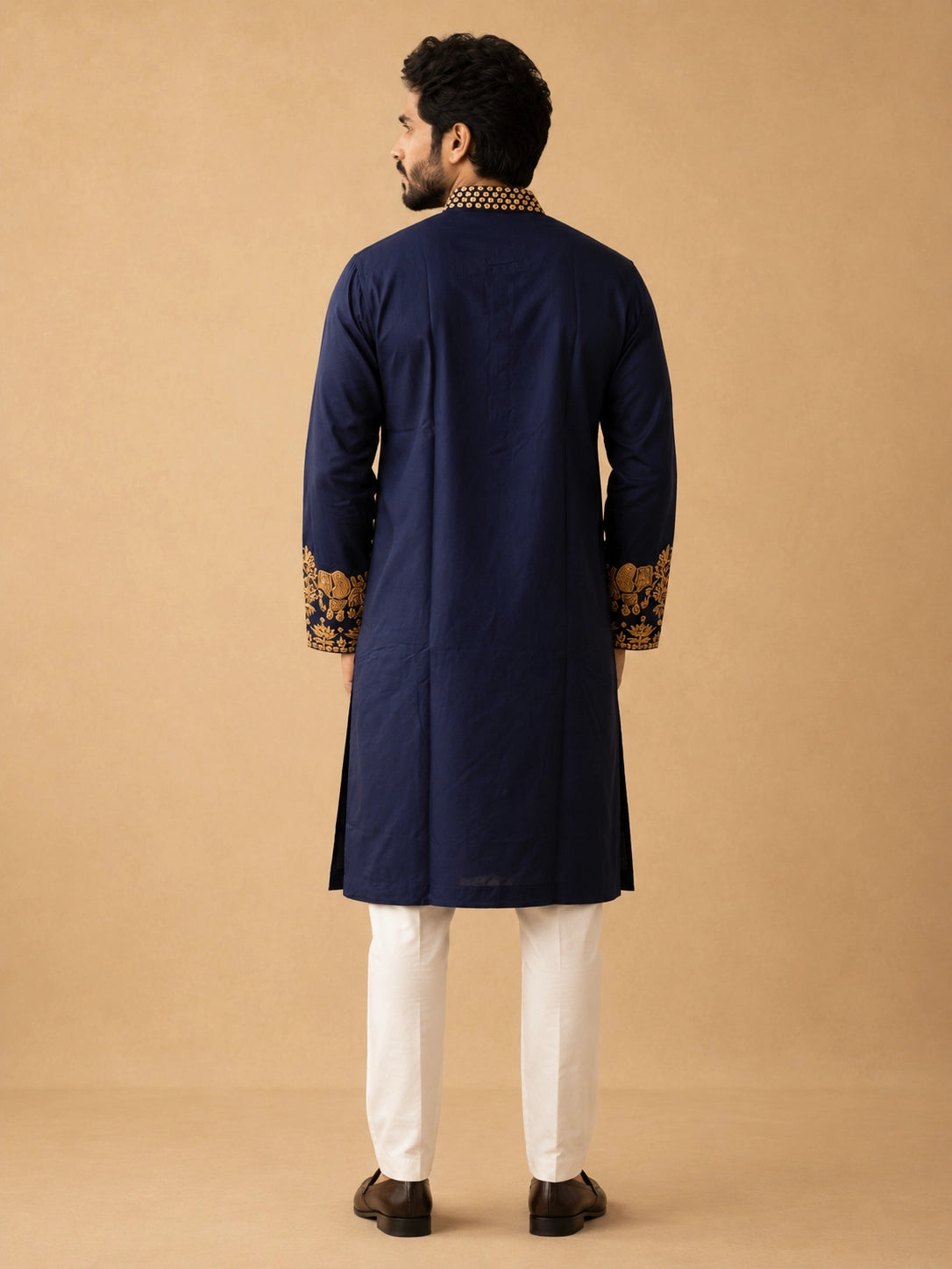 Man wearing a navy blue kurta pajama with intricate gold embroidery and elephant motifs.