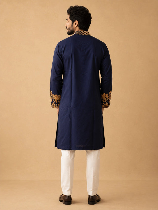 Man wearing a navy blue kurta pajama with intricate gold embroidery and elephant motifs.