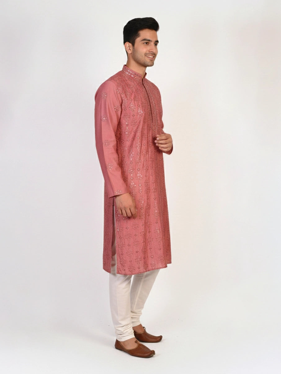 Man wearing a rose embroidered Kurta Pajama with white pants and brown jutti shoes.