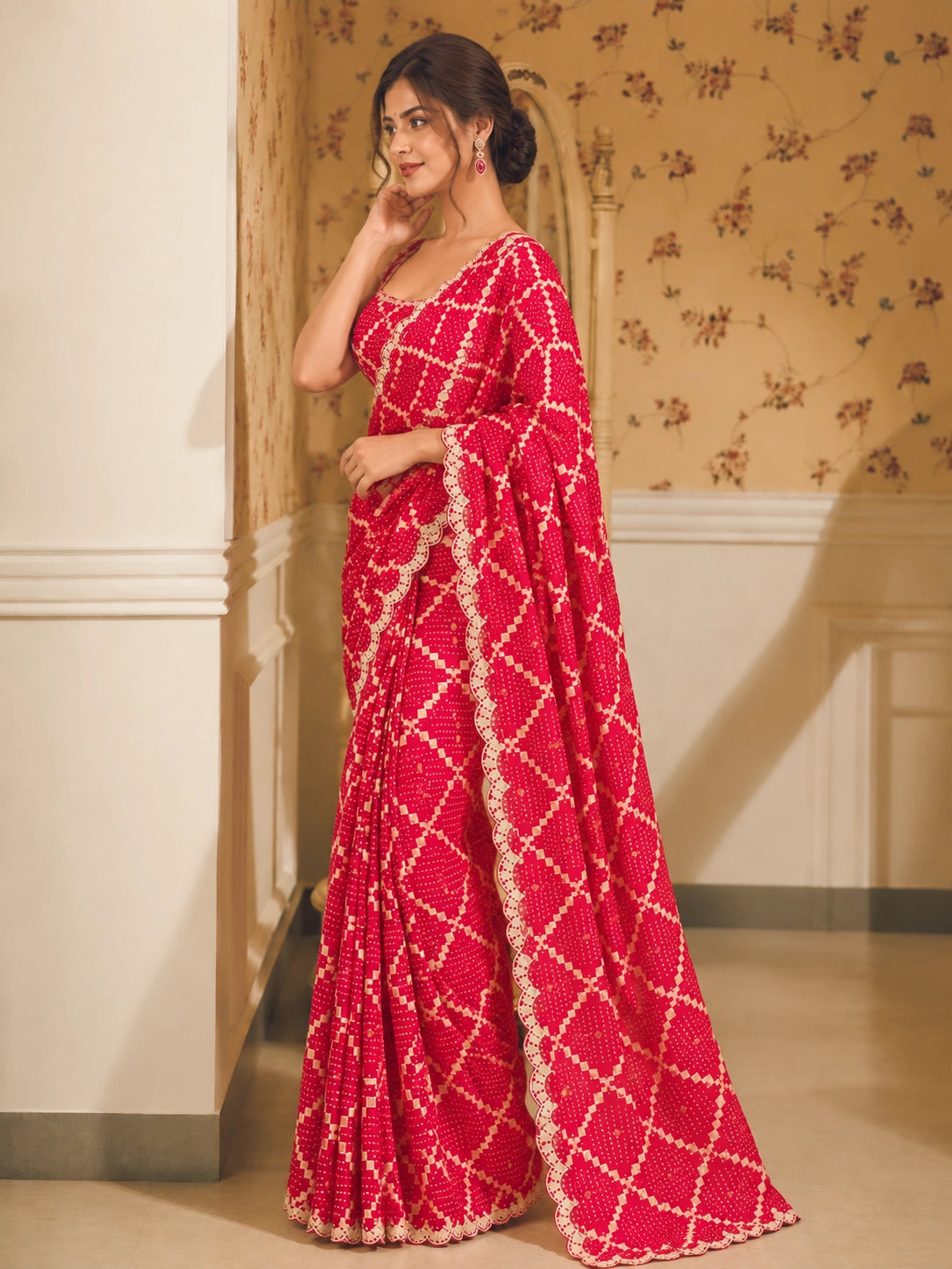 Woman in a vibrant red Bandhani saree with white patterns and scalloped border.