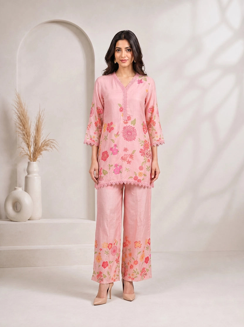 Woman wearing a pink floral print kurta with matching palazzo pants and lace trim.
