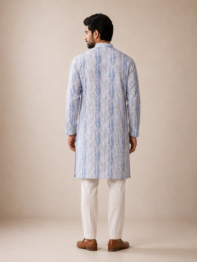 Man in a dust blue printed kurta, white pajama, and brown loafers.