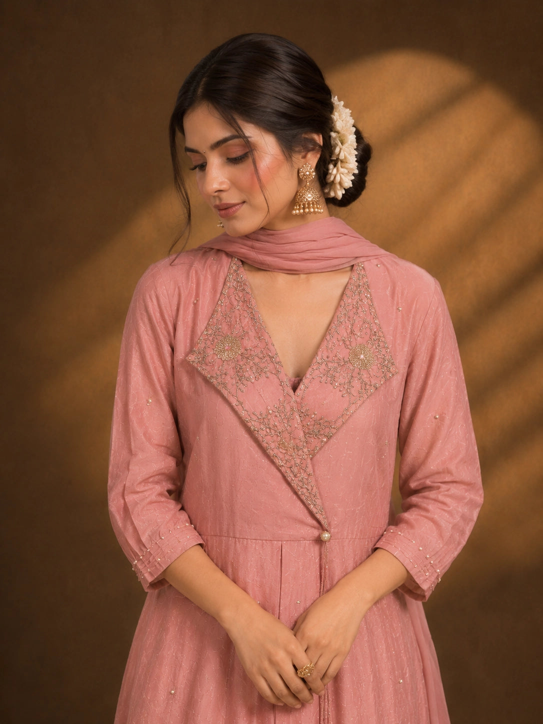 Woman in an elegant pink angrakha kurti and sharara set with intricate gold embroidery.