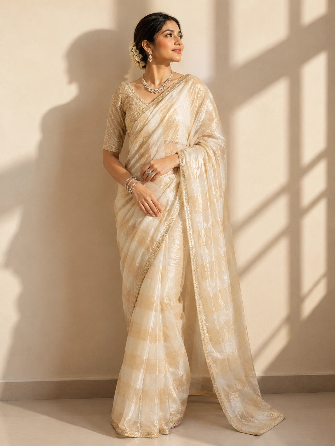 Woman in a cream and gold striped saree with an embroidered blouse.