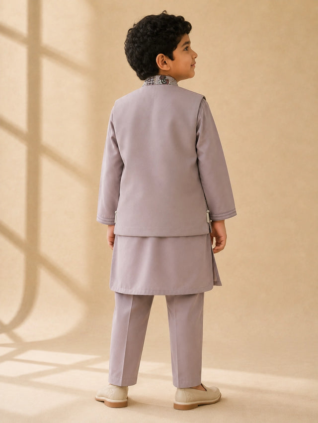 Young boy wearing a levendar kurta pajama with an intricately patterned waistcoat.