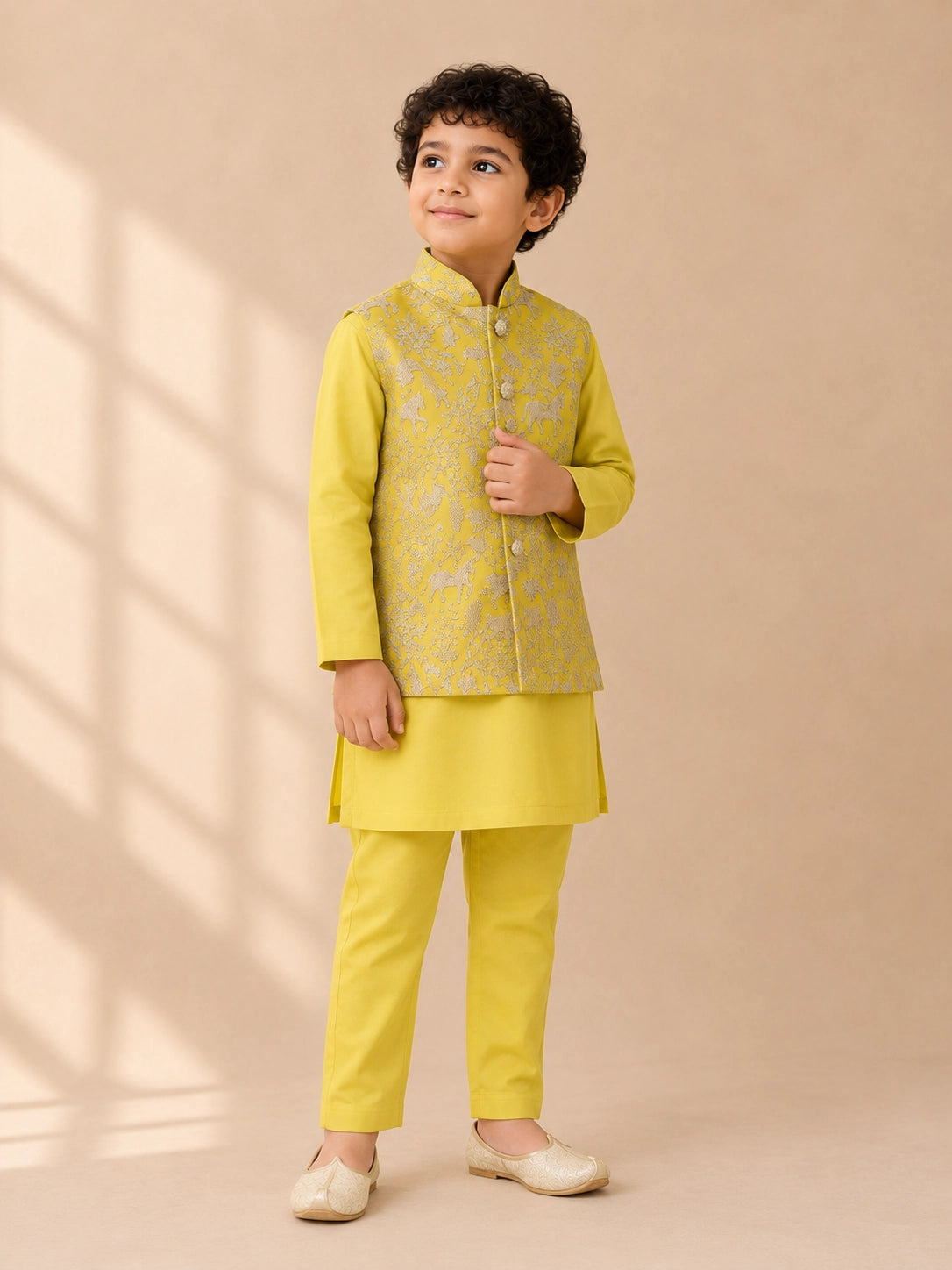 Young boy wearing a bright yellow kurta pajama set with an embroidered waistcoat.