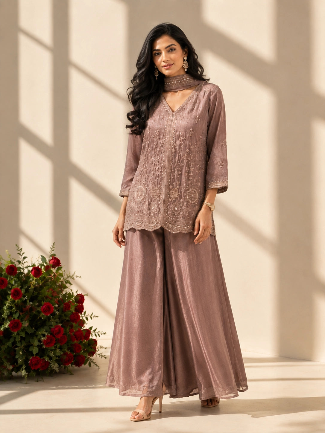 Woman in an elegant onion-colored embroidered kurti set with palazzo pants and matching scarf.