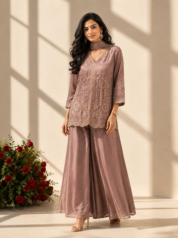 Woman in an elegant onion-colored embroidered kurti set with palazzo pants and matching scarf.