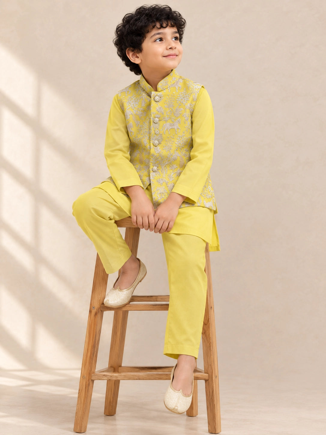 Young boy wearing a bright yellow kurta pajama set with an embroidered waistcoat.