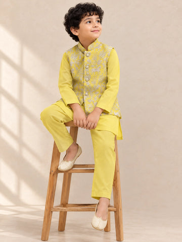 Young boy wearing a bright yellow kurta pajama set with an embroidered waistcoat.