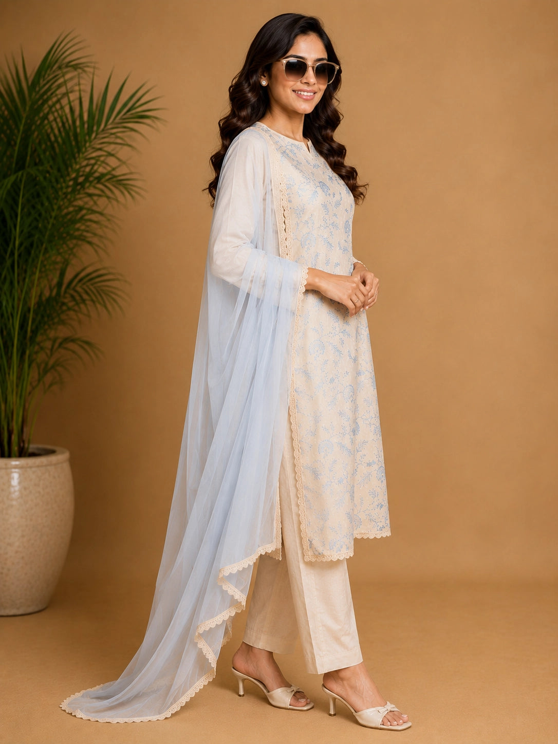Woman wearing a blue floral print Kurti Set with a sheer blue dupatta, seated in a chair.