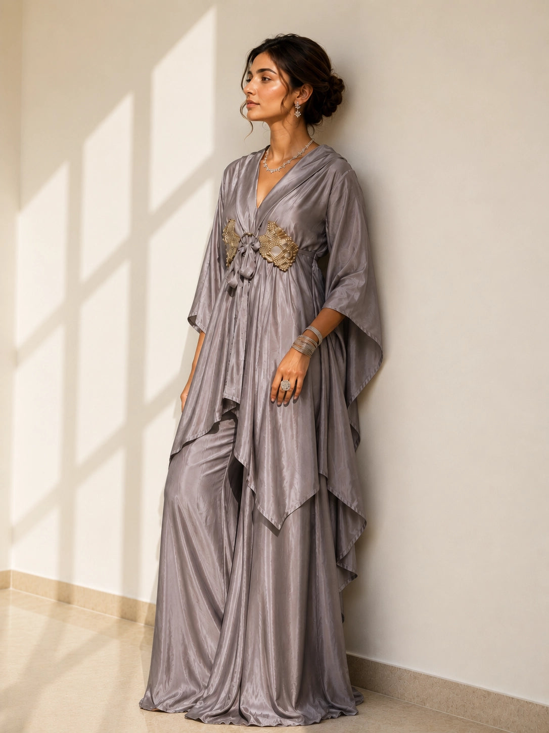 Woman in an elegant onion-colored layered kurti with golden waist detail and matching palazzo pants.