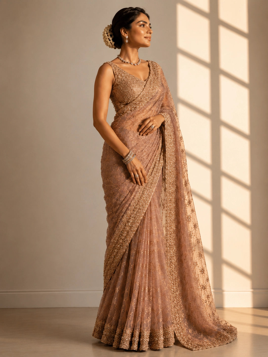 Woman in an elegant pink S3 embellished saree with intricate gold work and sleeveless blouse.