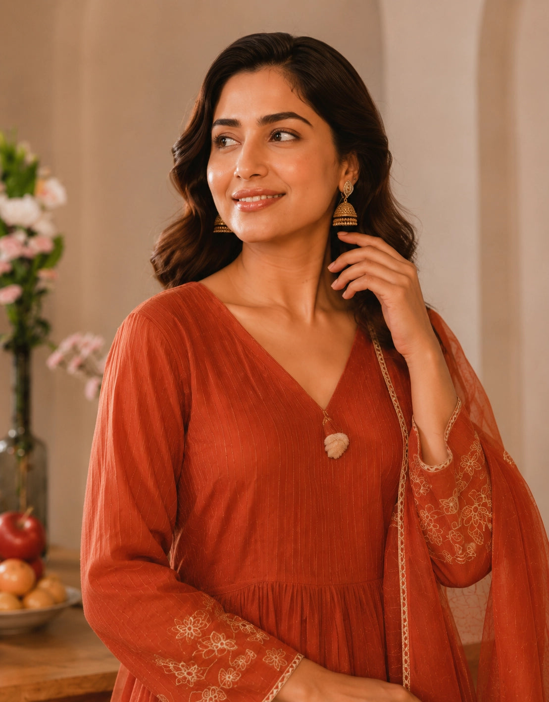 Woman smiling in a rust embroidered Anarkali kurti set with matching dupatta.