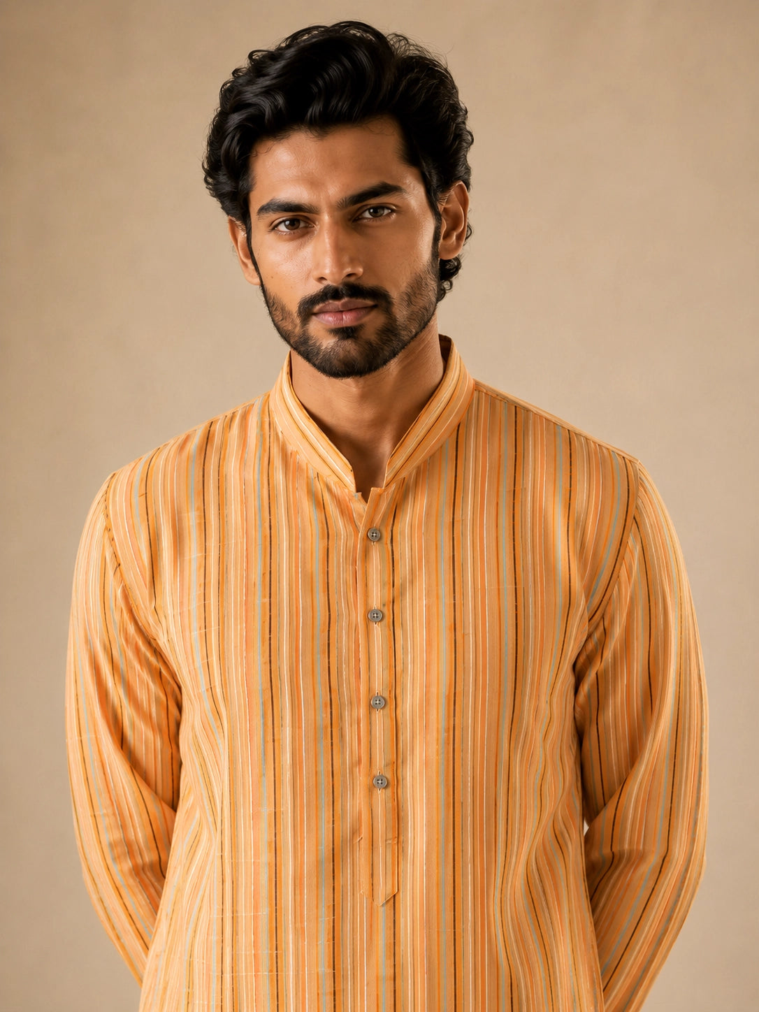 Man in a yellow striped kurta and white pajama, standing with hands behind back.