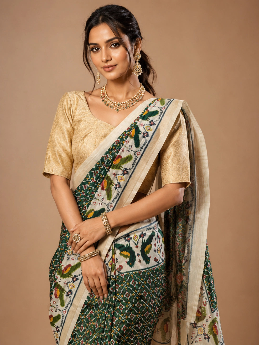 Woman in an elegant green Patola saree with a gold blouse and traditional jewelry.