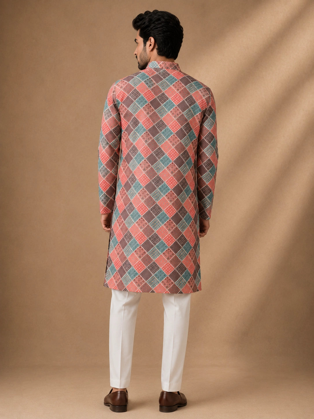 Man in a vibrant geometric diamond print kurta, white pajama, and brown loafers.