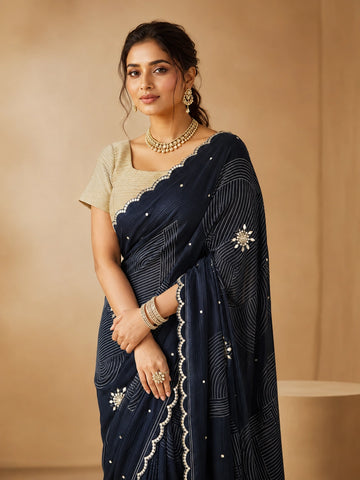 Woman wearing an elegant navy blue embroidered saree with a golden blouse and traditional jewelry.