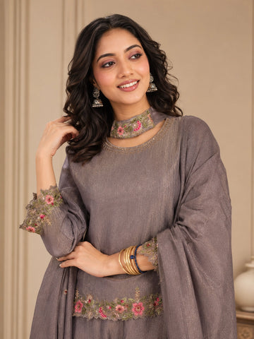 Woman wearing a pink embroidered choker neck Sharara with floral details on sleeves and hem.