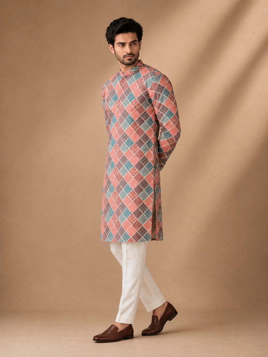 Man in a vibrant geometric diamond print kurta, white pajama, and brown loafers.