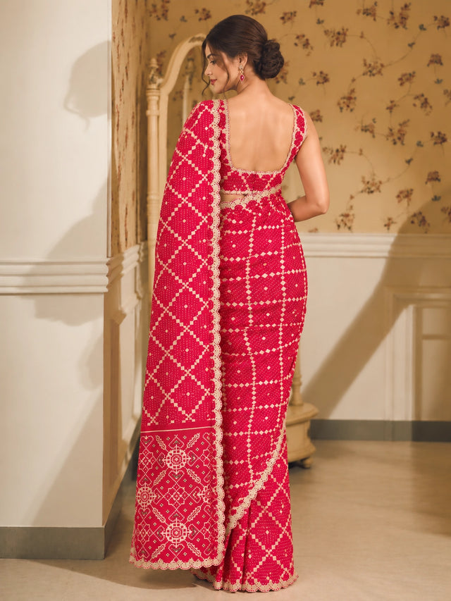 Woman in a vibrant red Bandhani saree with white patterns and scalloped border.
