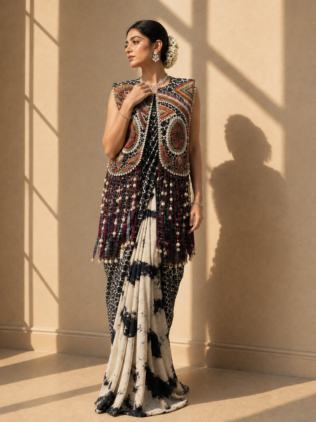 Woman wearing a black and white tie-dye saree with a vibrant, heavily embellished sleeveless jacket.