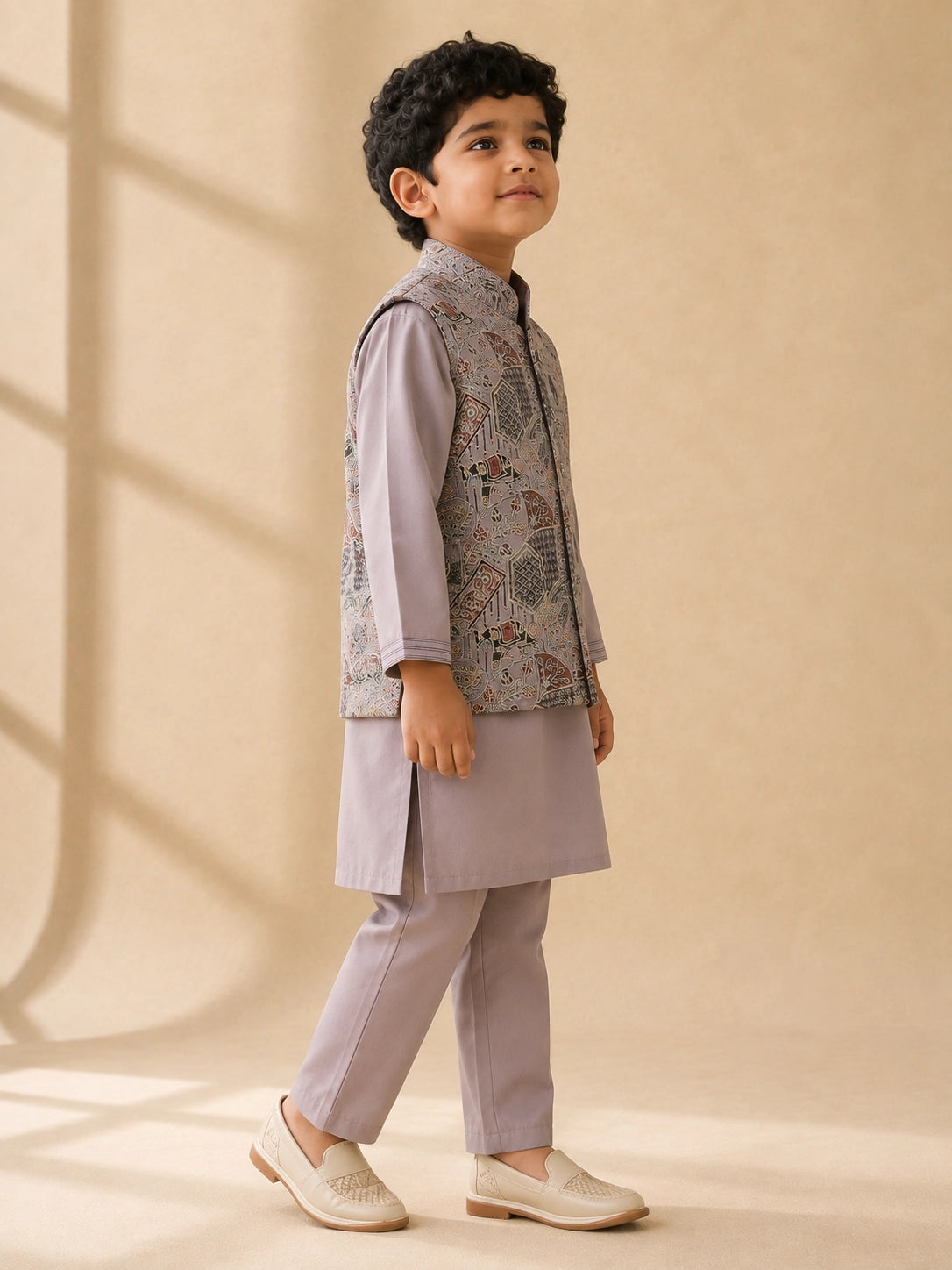 Young boy wearing a levendar kurta pajama with an intricately patterned waistcoat.