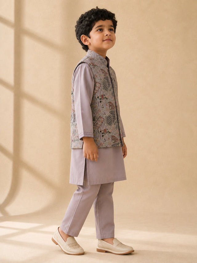 Young boy wearing a levendar kurta pajama with an intricately patterned waistcoat.