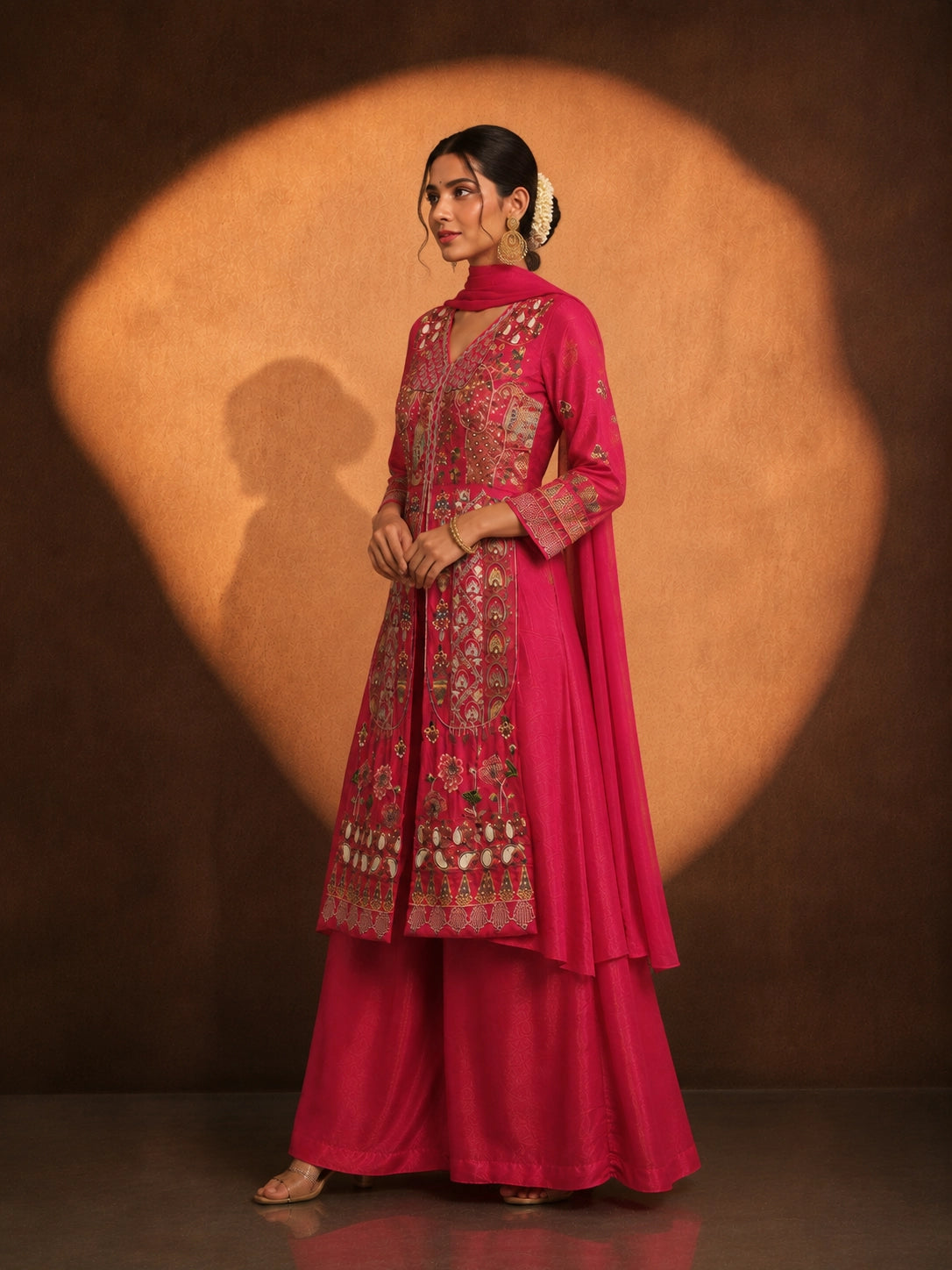 Woman in a vibrant rani pink embroidered kurti set with a flowing silhouette.