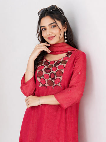 Woman wearing a Rani red Sharara with a geometric print yoke and matching dupatta, styled with pearl earrings.