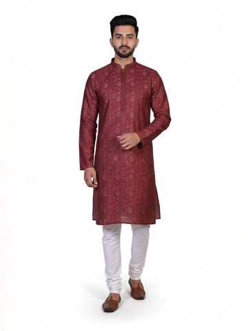 Man wearing a maroon printed kurta with white pants and brown shoes, showcasing traditional Indian attire.