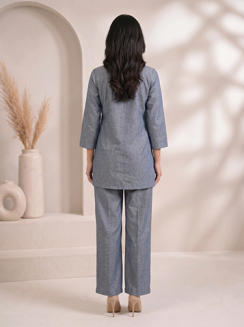 Woman wearing a blue cotton co-ord set with embroidered details on the top and straight-leg pants.
