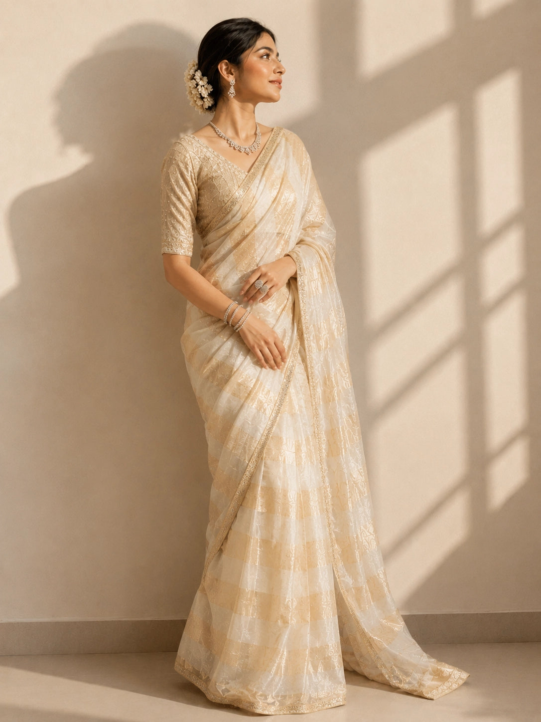 Woman in a cream and gold striped saree with an embroidered blouse.