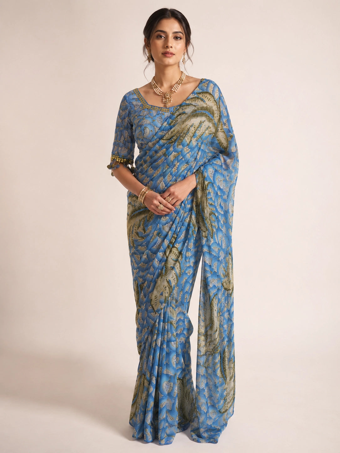Woman wearing a sky blue  printed saree with olive feather patterns.