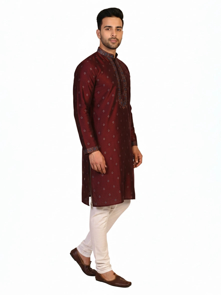 Man wearing a maroon kurta with a diamond pattern and embroidered neckline, paired with cream pants.