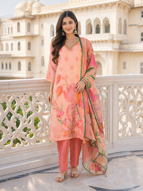 Woman wearing a pink floral print kurta set with shimmering pink pants and silver jhumka earrings.